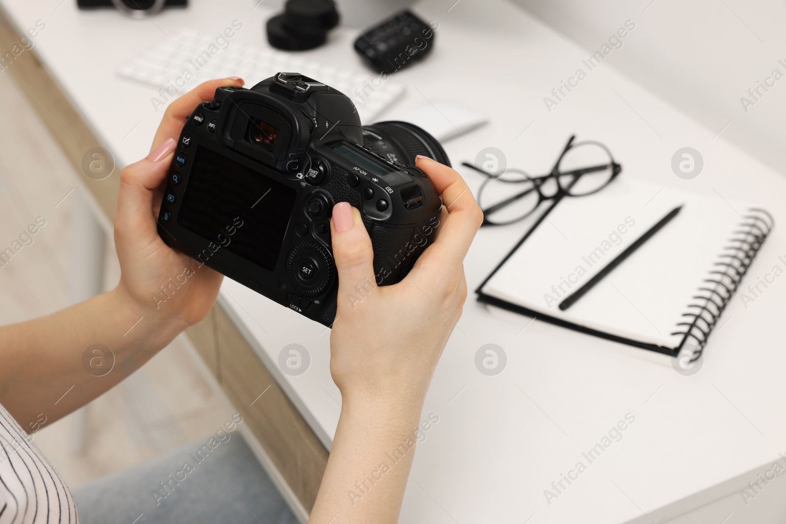 Photo of Photographer with camera at white table indoors, closeup