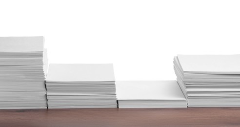 Photo of Stacks of paper sheets on wooden table against white background