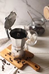 Photo of Brewed coffee in moka pot and beans on white wooden table