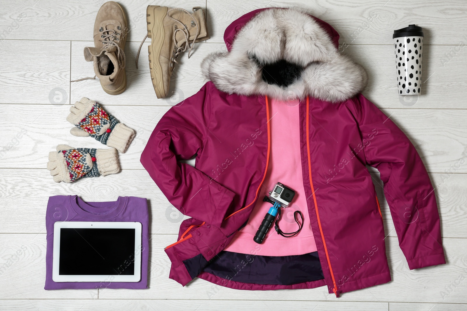 Photo of Set of warm clothes and devices on wooden background, flat lay. Winter vacation