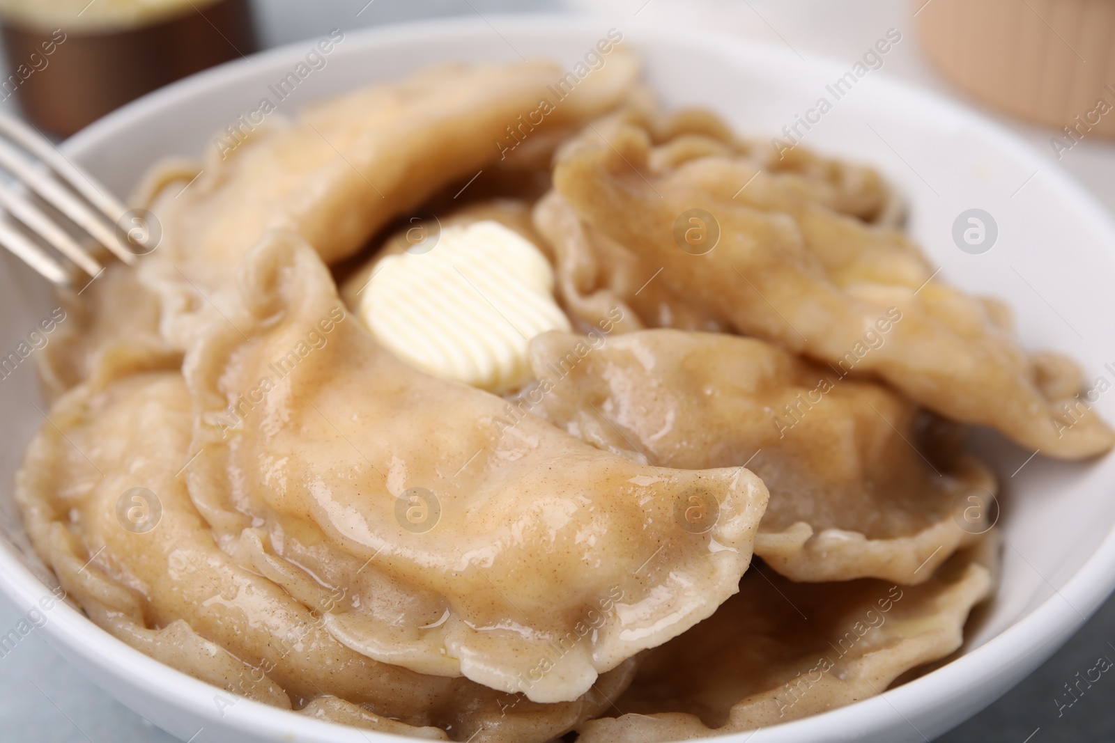 Photo of Bowl of delicious dumplings (varenyky) with cottage cheese and butter, closeup