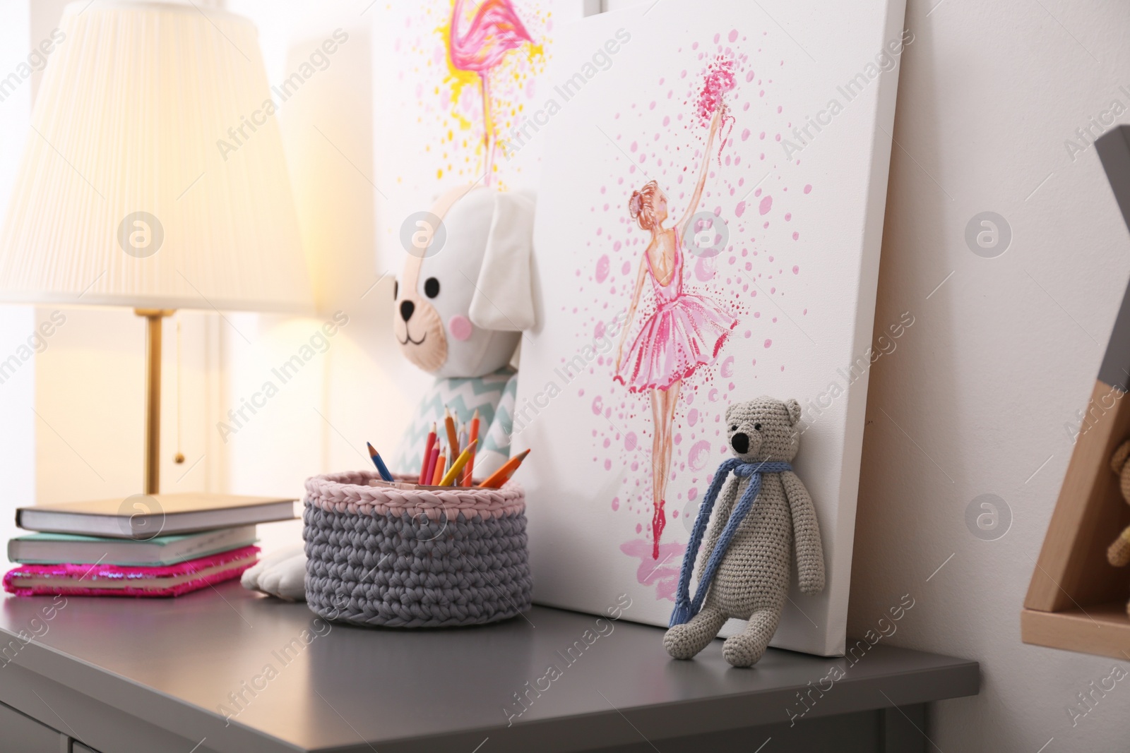 Photo of Picture and stationery with toys on chest of drawers in children's room. Interior design