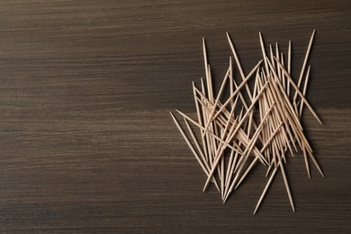 Disposable toothpicks on wooden background, flat lay. Space for text