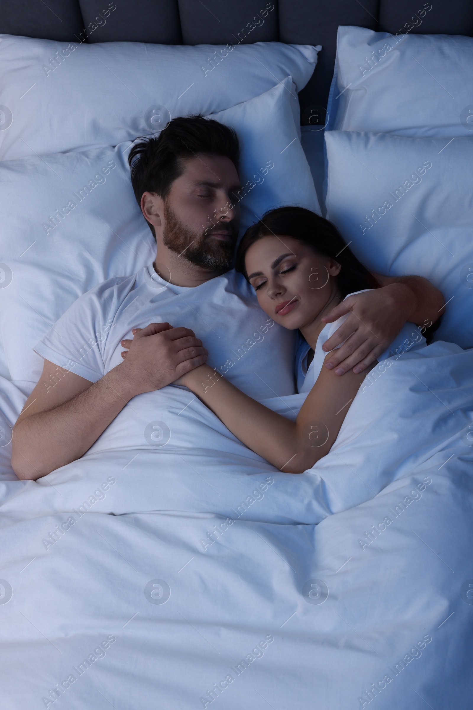 Photo of Lovely couple sleeping together in bed at night, top view