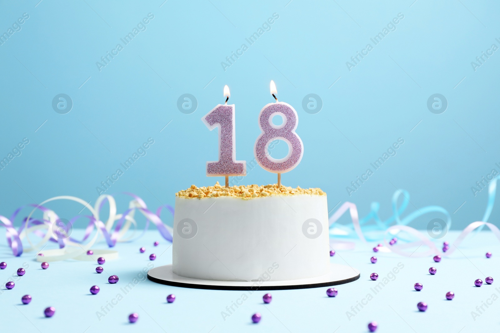 Photo of Coming of age party - 18th birthday. Delicious cake with number shaped candles on light blue background