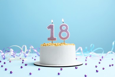 Coming of age party - 18th birthday. Delicious cake with number shaped candles on light blue background