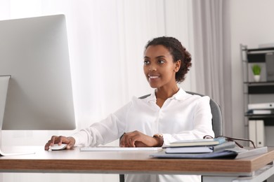Photo of Smiling African American intern working with computer at table in office