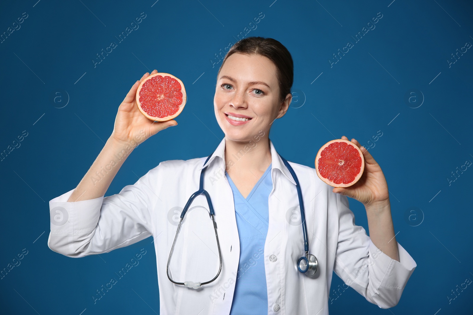 Photo of Nutritionist with ripe grapefruit on blue background