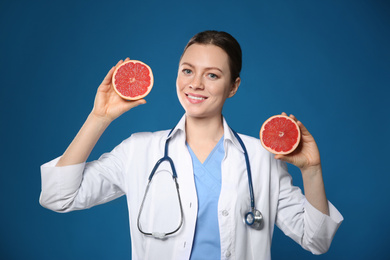 Photo of Nutritionist with ripe grapefruit on blue background
