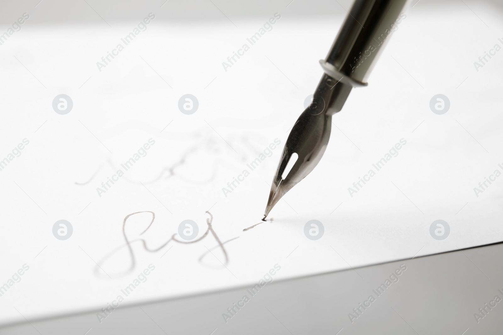 Photo of Signing on sheet of paper with fountain pen against light grey background, closeup. Space for text