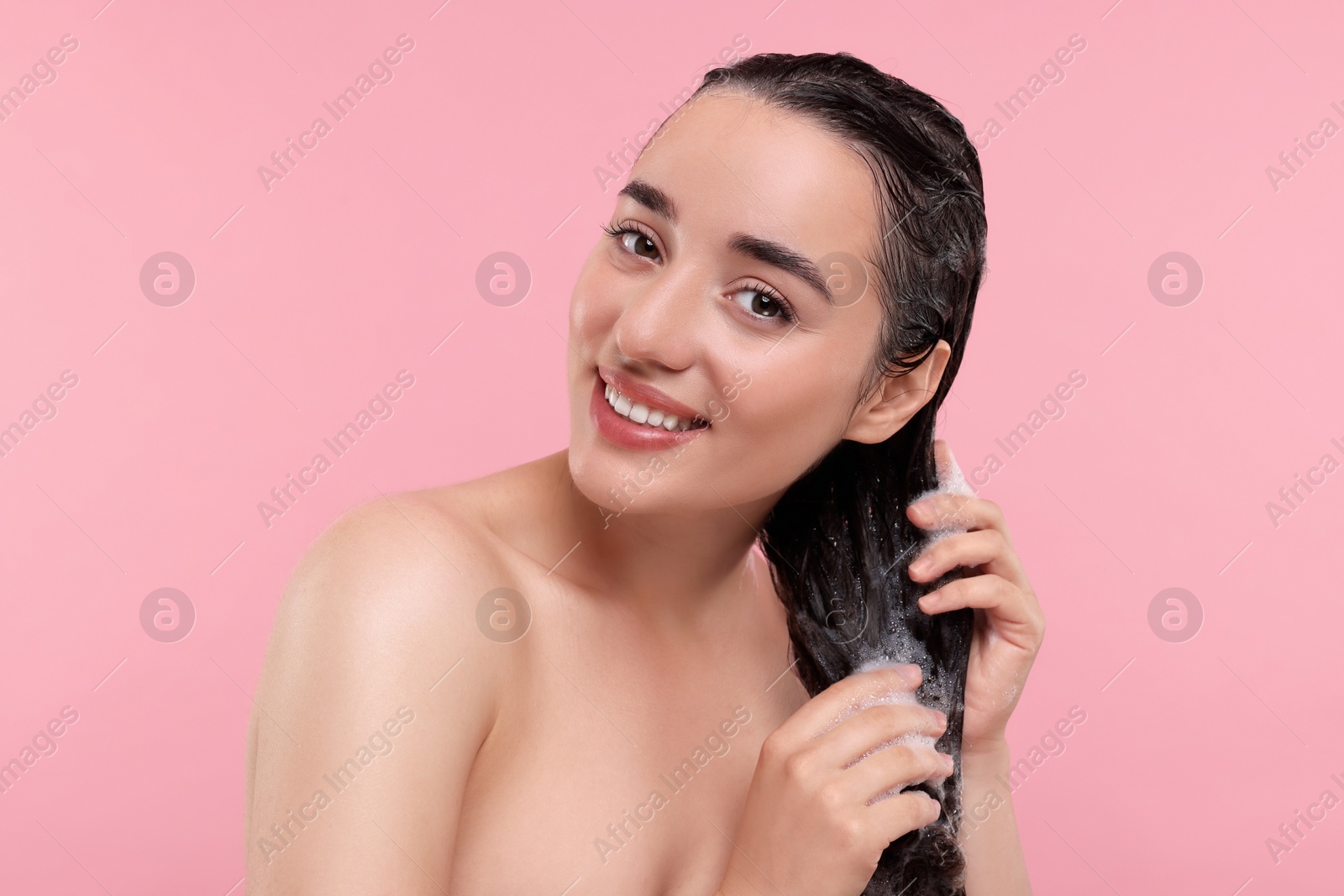 Photo of Portrait of beautiful happy woman washing hair on pink background