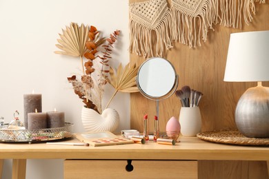 Dressing table with mirror, makeup products and decor in room