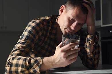 Photo of Addicted man with alcoholic drink at table in kitchen