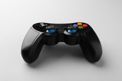 Black wireless game controller on light grey background