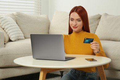 Photo of Happy woman with credit card using laptop for online shopping at home