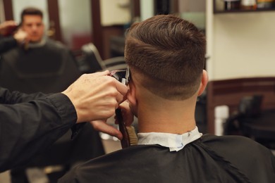 Photo of Professional hairdresser making stylish haircut in salon, back view