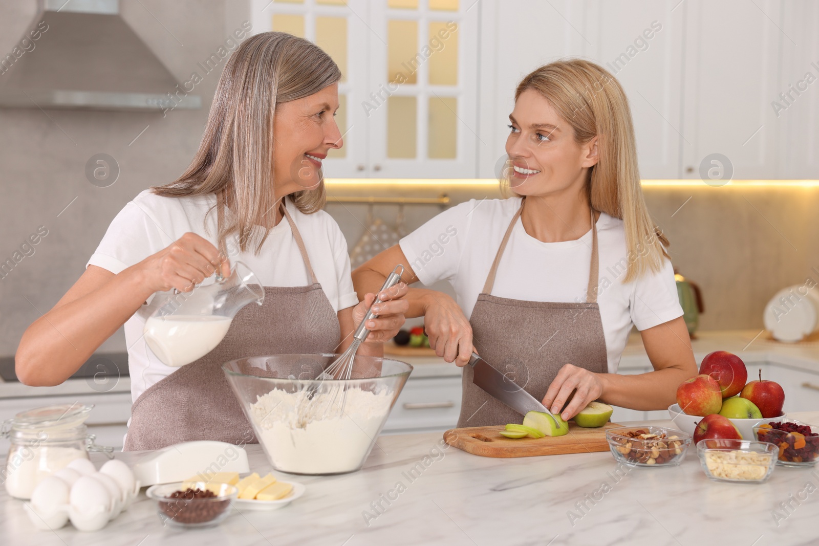 Photo of Happy mature mother and her daughter cooking together at kitchen