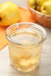 Photo of Delicious quince drink in glass and fresh fruits on wooden table, closeup