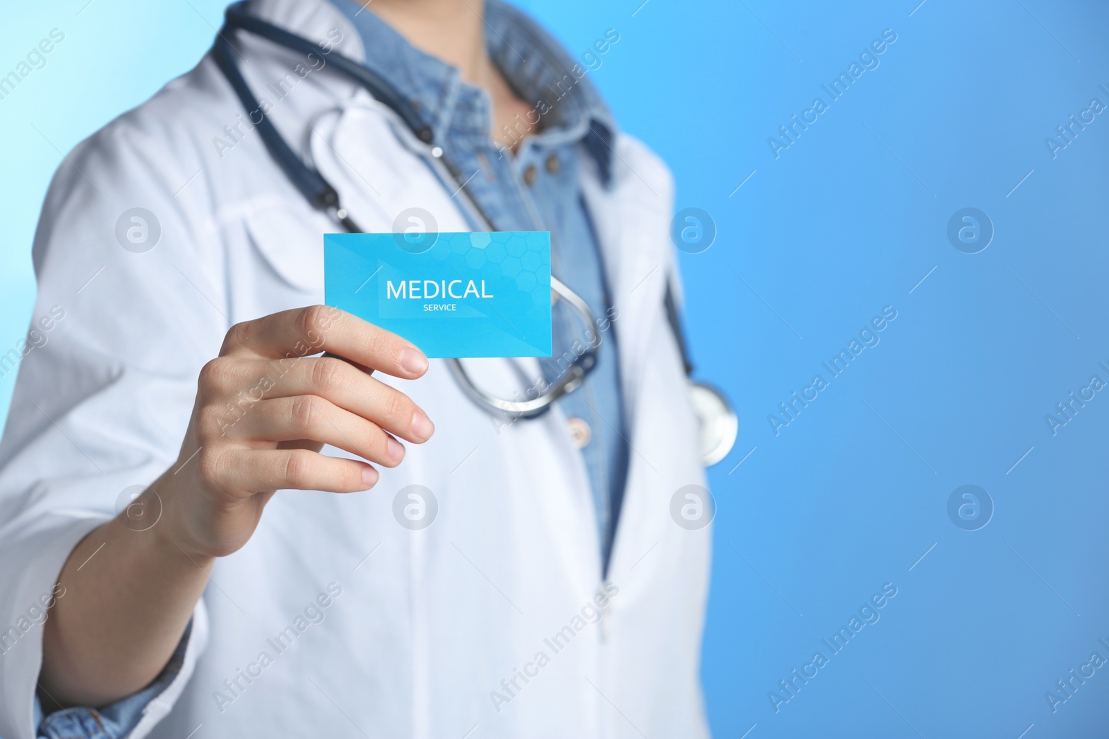 Photo of Doctor holding business card on color background, closeup with space for text. Medical service