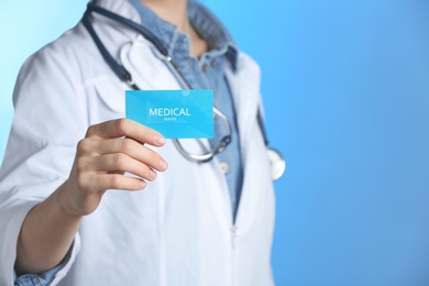 Photo of Doctor holding business card on color background, closeup with space for text. Medical service