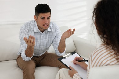 Photo of Unhappy man having session with his therapist indoors