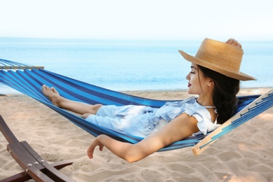 Photo of Young woman resting in comfortable hammock at seaside