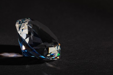 Photo of Beautiful dazzling diamond on dark background, closeup. Space for text