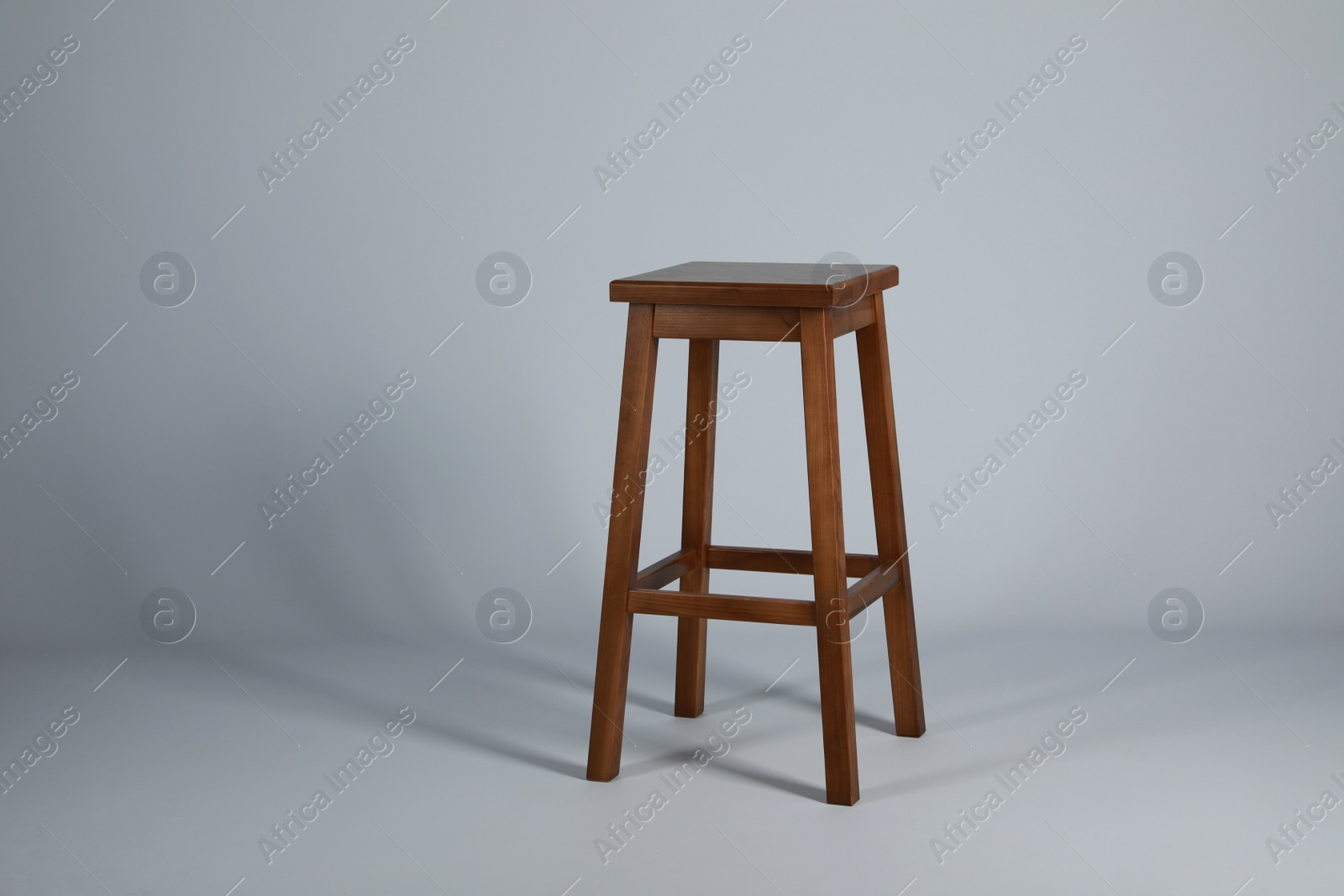 Photo of Stylish wooden stool on light grey background. Interior element