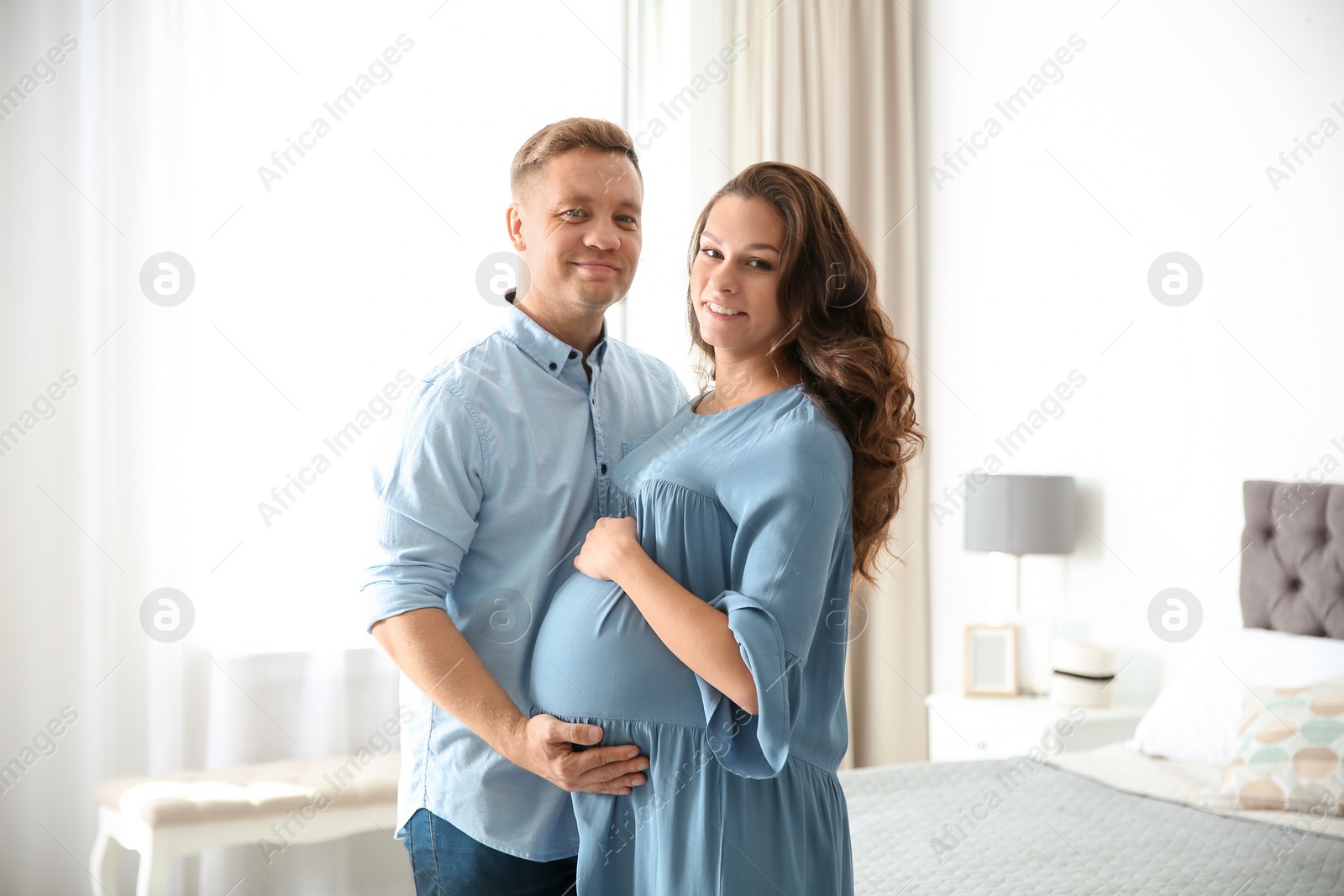 Photo of Pregnant woman with her husband in bedroom. Happy young family