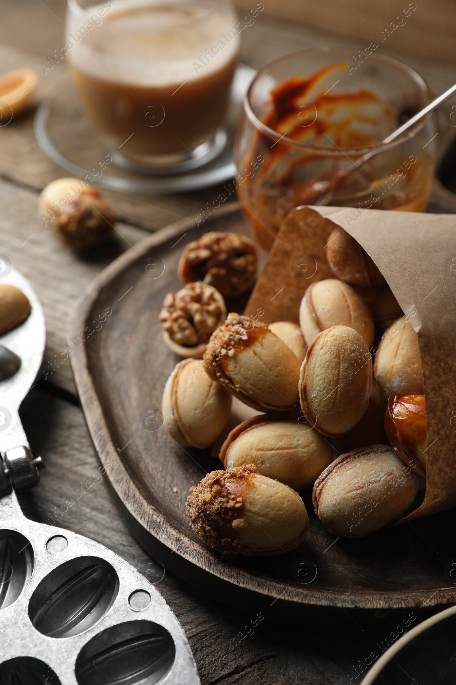 Photo of Freshly baked homemade walnut shaped cookies, boiled condensed milk and baking dish on wooden table