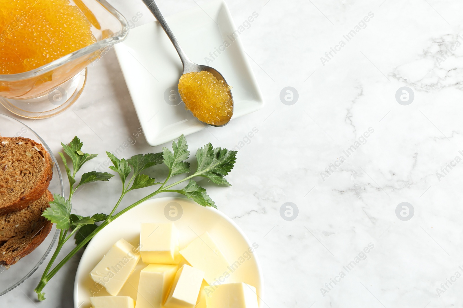 Photo of Fresh pike caviar, butter, bread and parsley on white marble table, flat lay. Space for text