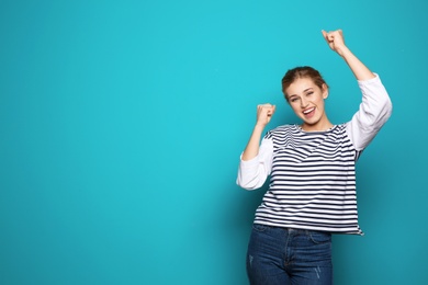 Photo of Happy young woman celebrating victory on color background. Space for text
