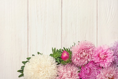 Beautiful aster flowers and space for text on wooden background, flat lay