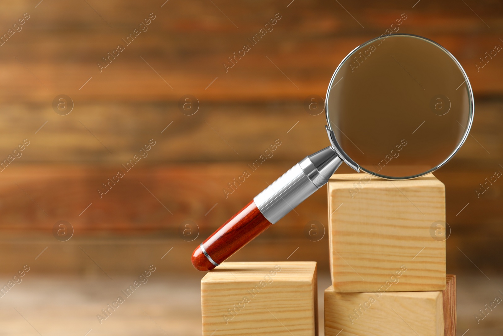 Photo of Closeup view of magnifier glass and wooden cubes on blurred background, space for text. Find keywords concept