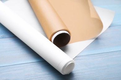 Photo of Rolls of baking paper on light blue wooden table, closeup