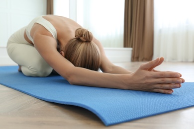 Young woman practicing extended child asana in yoga studio. Utthita Balasana pose