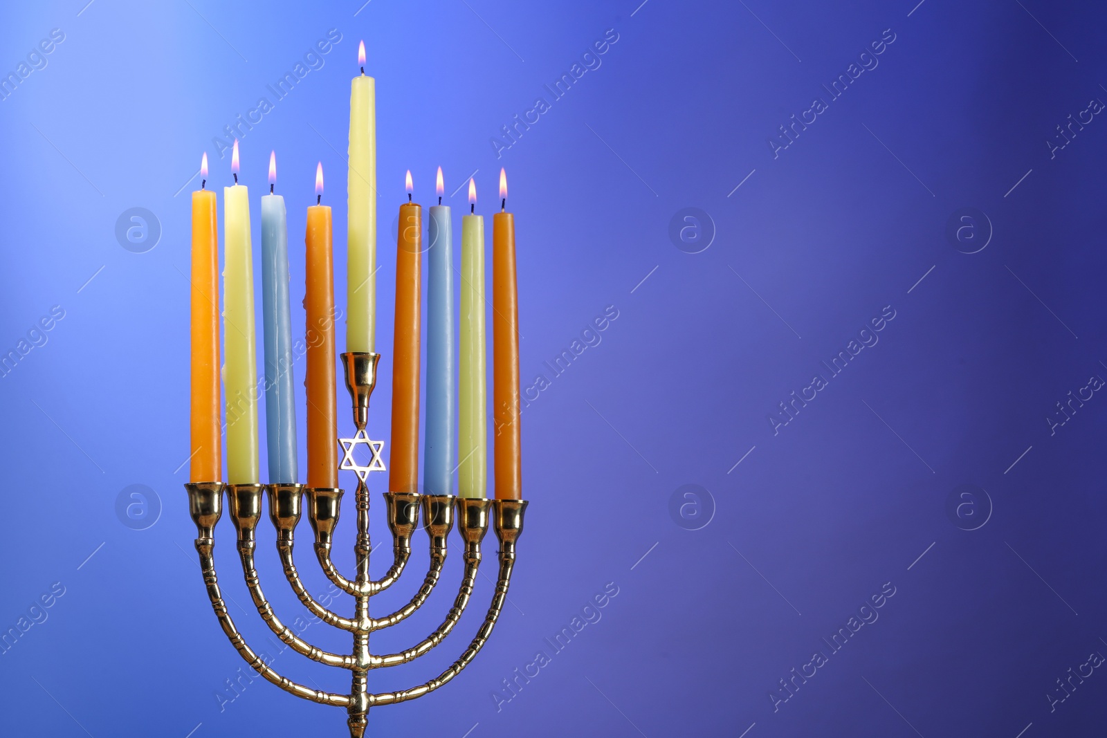 Photo of Hanukkah celebration. Menorah with burning candles on blue background, space for text