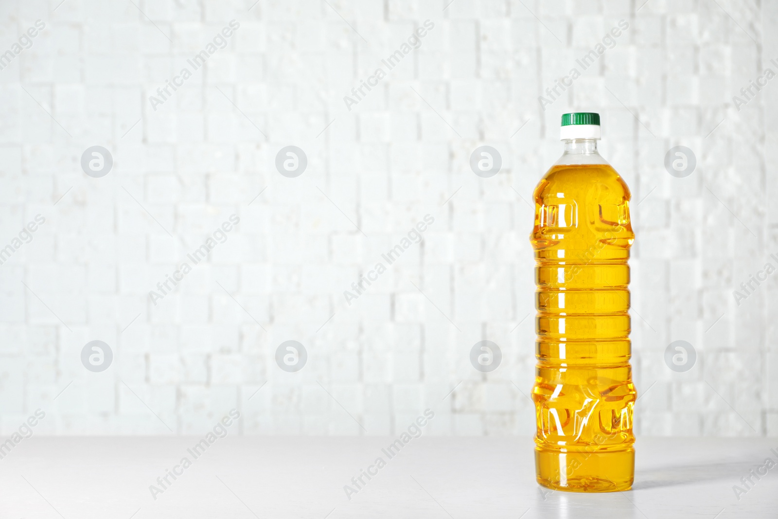 Photo of Bottle of oil on table against light background. Space for text