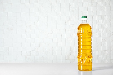 Photo of Bottle of oil on table against light background. Space for text