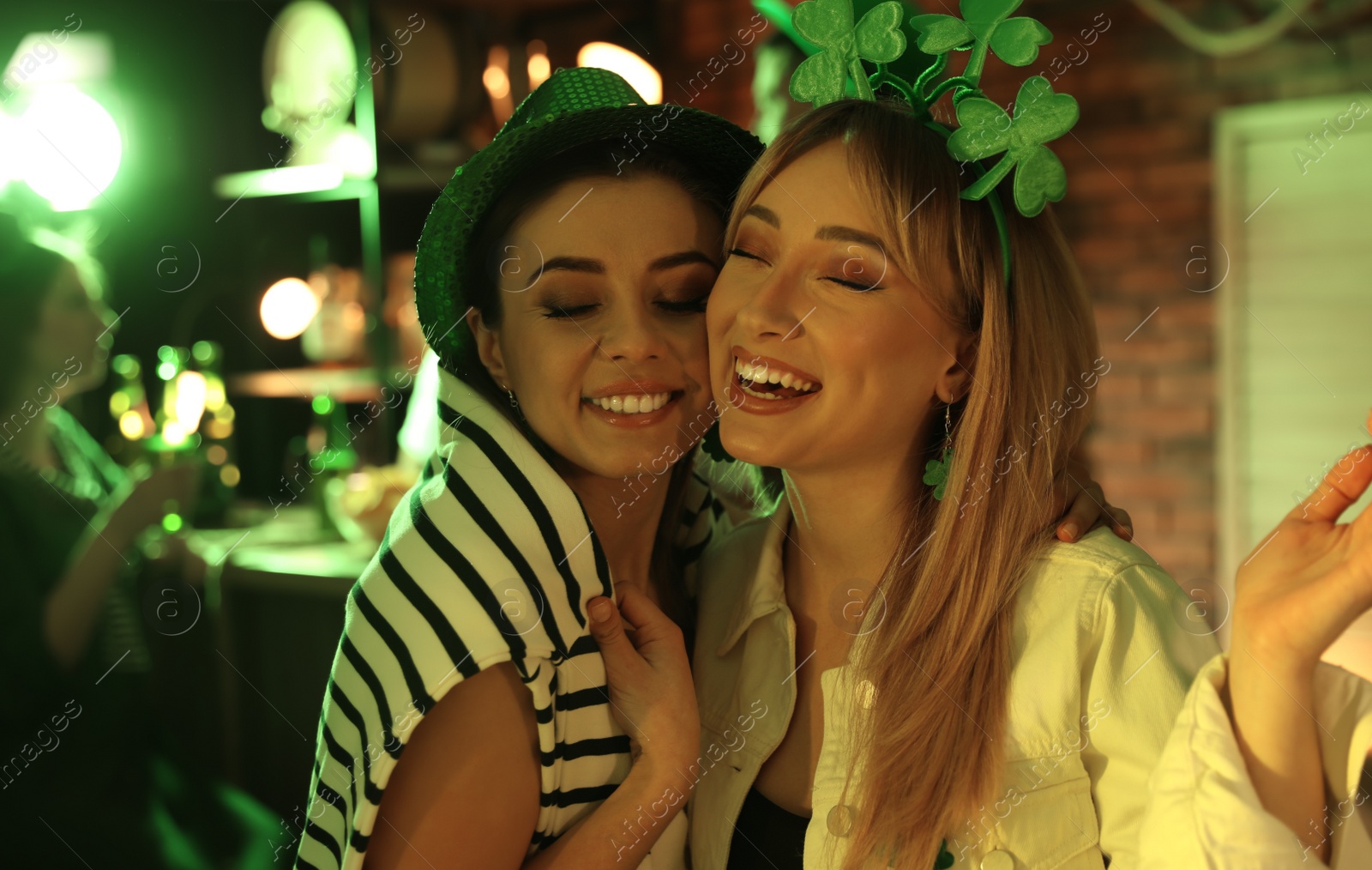 Photo of Happy women with festive accessories in pub. St Patrick's day celebration