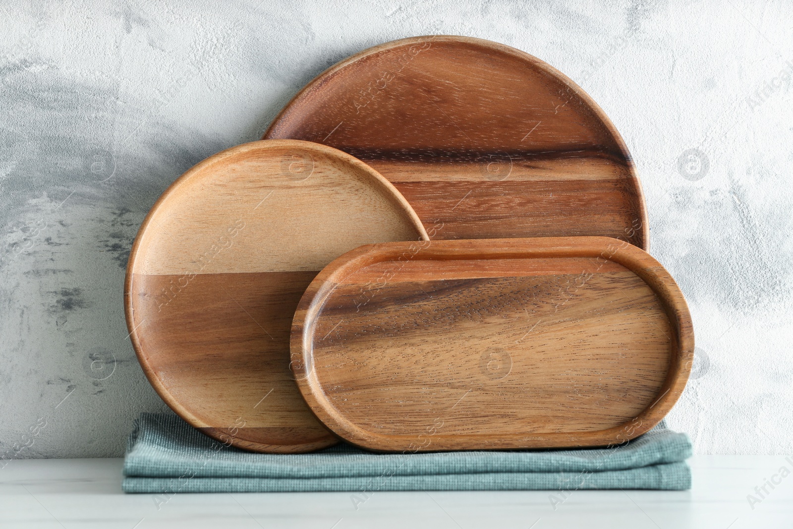 Photo of Set of wooden dishware on white marble table against textured wall