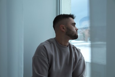 Photo of Sad man looking at window at home