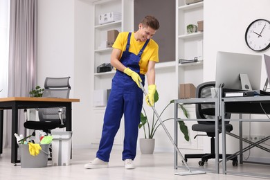 Photo of Cleaning service. Man washing floor with mop in office