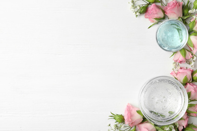 Flat lay composition with cosmetic gel and beautiful flowers on white wooden table. Space for text