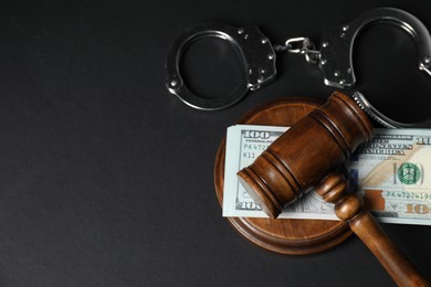 Photo of Law gavel, dollars and handcuffs on grey table, flat lay. Space for text