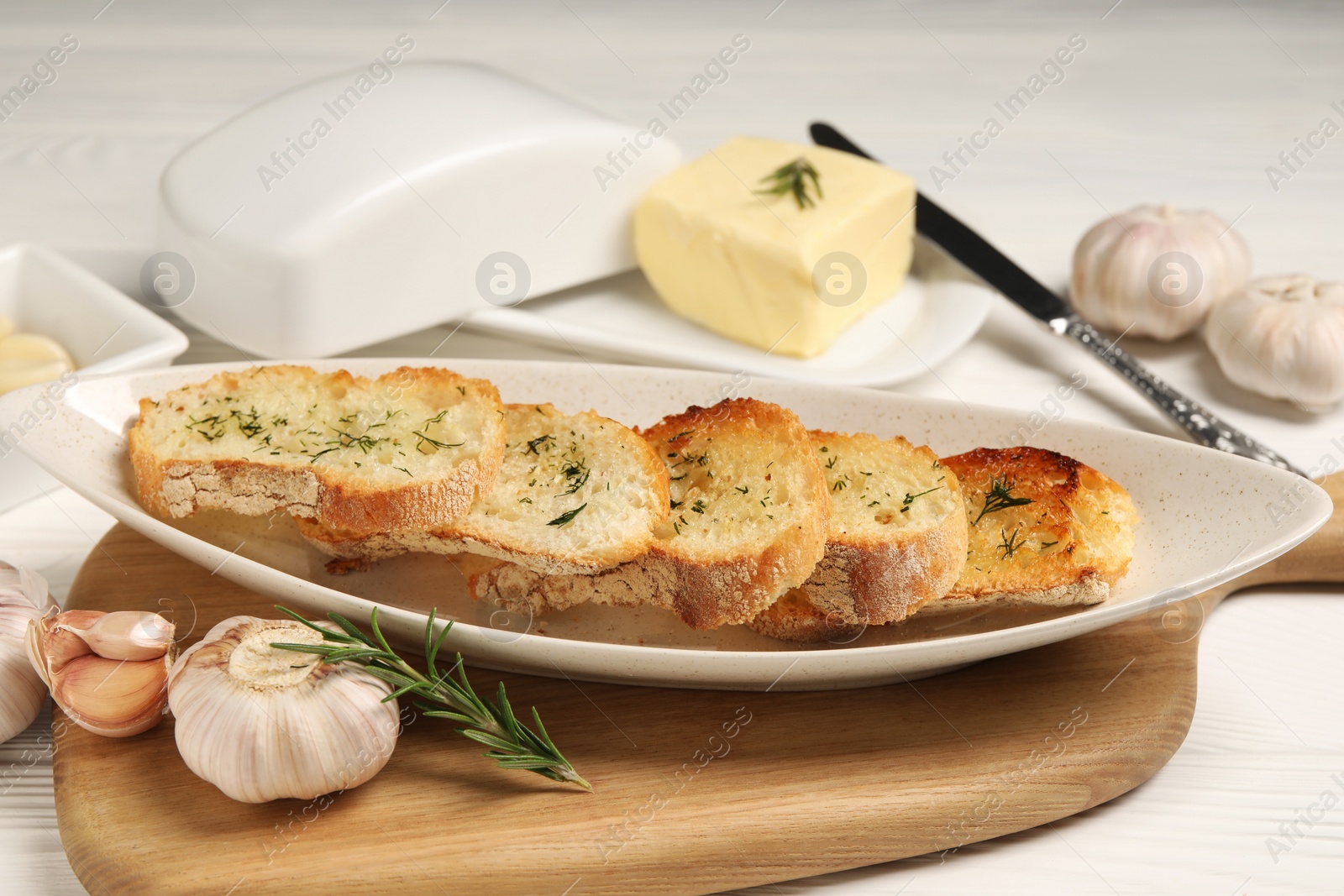 Photo of Tasty baguette with garlic and dill served on white table