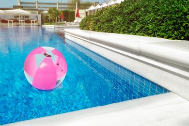 Inflatable beach ball floating in outdoor swimming pool 