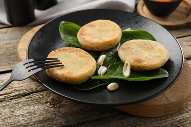 Plate with healthy dish high in vegetable fats and fork on wooden table, closeup