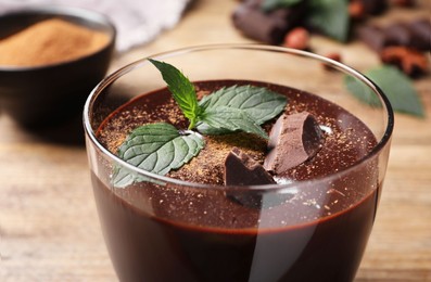Photo of Glass of delicious hot chocolate with fresh mint on wooden table, closeup
