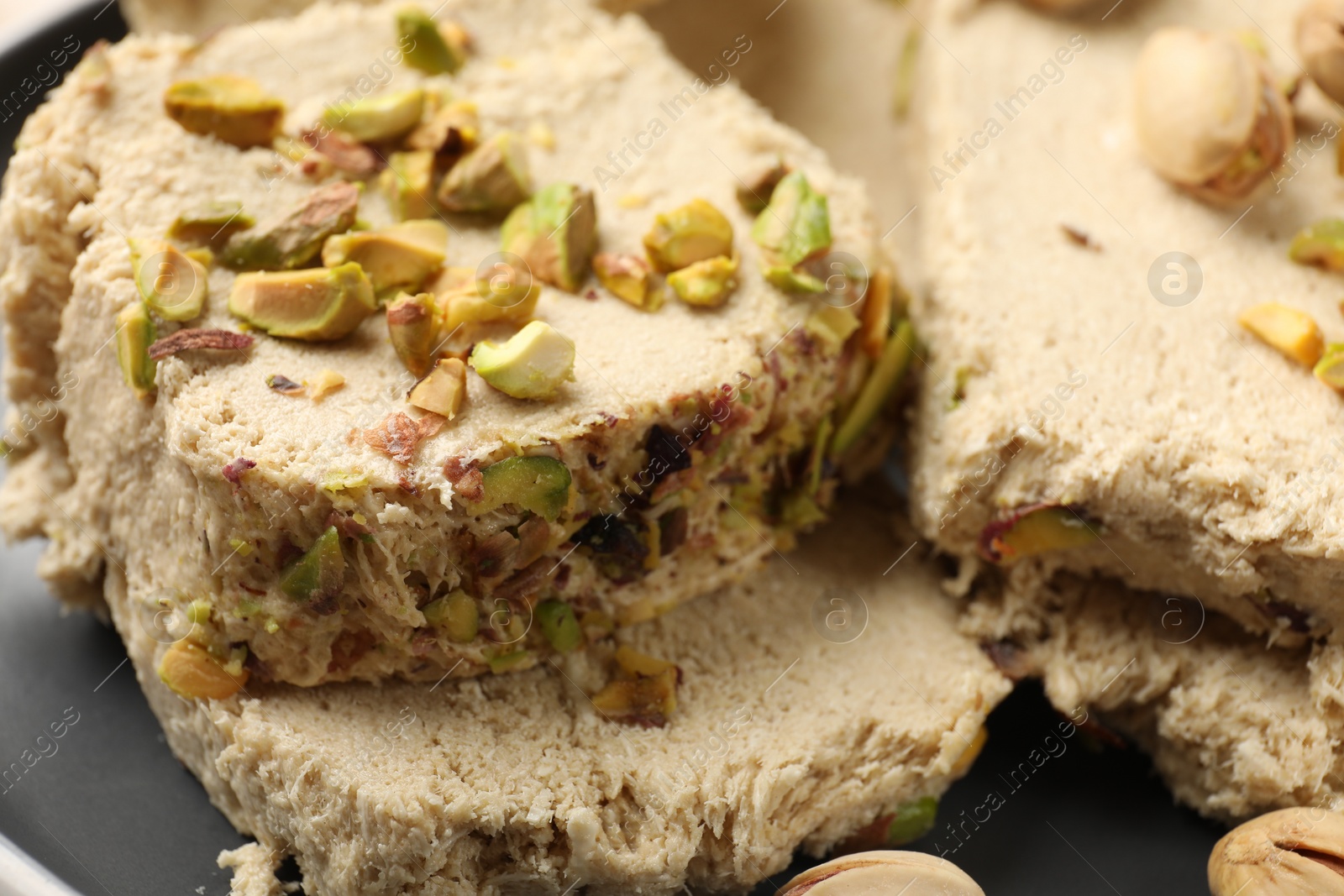 Photo of Pieces of tasty halva with pistachios on table, closeup